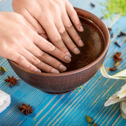 Mains dans de l'eau chaude pour enlever des faux-ongles, retirer sa manucure.