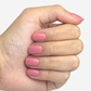Main fermée avec des faux ongles rose pale sur les ongles