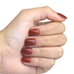 Main fermée avec faux ongles marron brillants, courts, visibles
