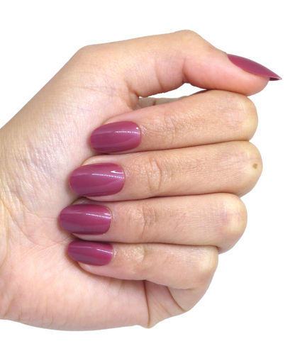 Main fermée portant faux ongles roses forme amande taille moyenne brillants